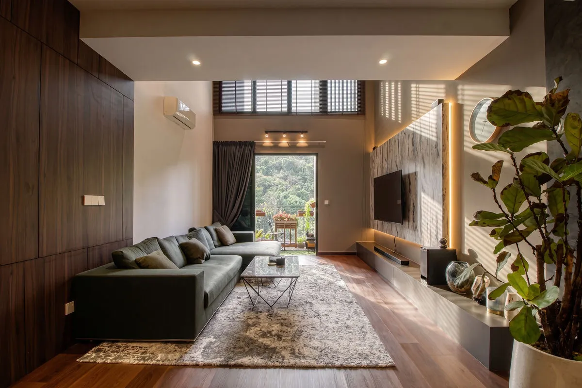 Living room with a green sectional sofa, timber wall panelling and forest views
