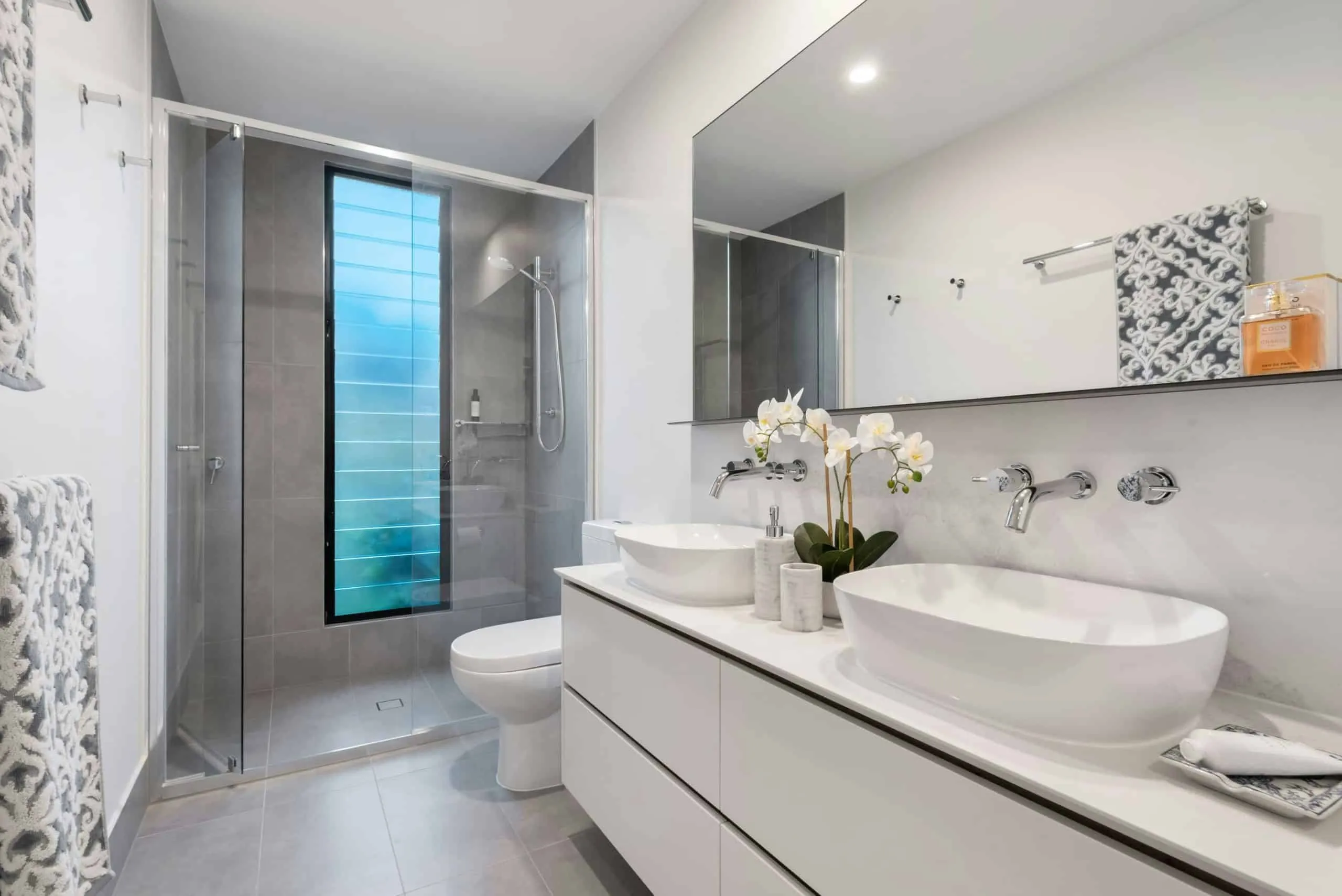Finished bathroom with double vanity and glass-enclosed shower