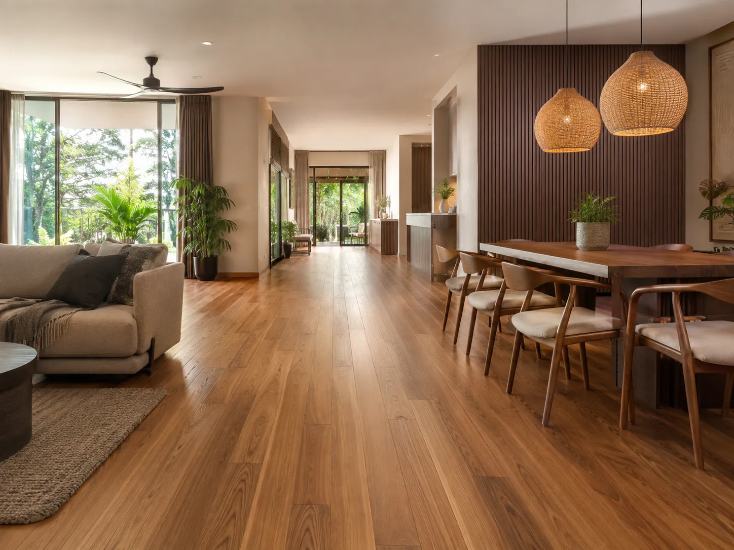 Living and dining area with warm-toned wide-plank wood flooring, a wood slat feature wall, and glass doors opening onto a green outdoor view